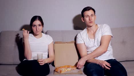 La-feliz-pareja-comiendo-una-pizza-y-ver-una-película-en-el-sofá