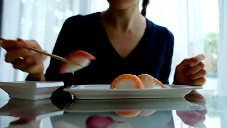 joven-caucásica-comer-sushi-en-restaurante-japonés