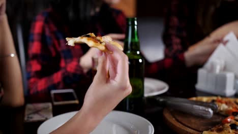 Gruppe-von-fröhlichen-Mädchen-im-Restaurant-lecker-Pizza-essen-und-Bier-aus-Flaschen-trinken.