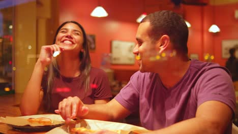 Una-joven-pareja-comiendo-en-un-centro-de-la-ciudad-de-pizzeria