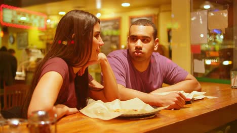 Una-joven-pareja-comiendo-en-un-centro-de-la-ciudad-de-pizzeria