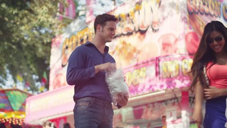 A-couple-eating-cotton-candy-and-sharing-sunglasses-at-a-fair