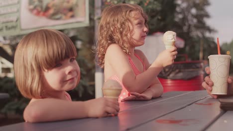 Dos-hermanas-comer-helados-con-su-familia-en-la-mesa-de-día-de-campo