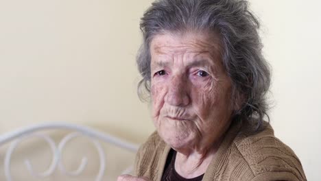 Unhealthy-old-woman-eating,-looking-camera-at-home