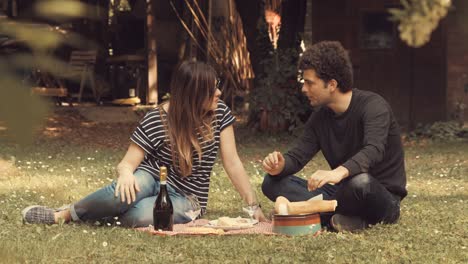 Young-couple-picnics-and-talks-in-the-garden-in-a-sunny-day