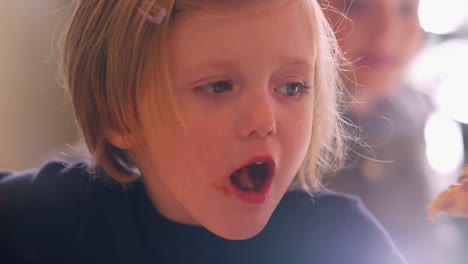 Close-up-of-a-cute-little-girl-taking-a-big-bite-of-pizza-at-home