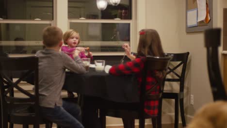 Three-kids-eating-spaghetti-and-meatballs-at-the-dinner-table-together