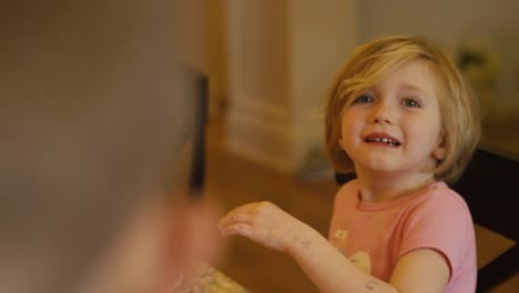 Una-niña-jugando-con-sus-tortitas-con-las-manos,-hablando-y-sonriendo