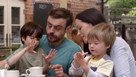 Familia-sentarse-en-la-mesa-de-café-al-aire-libre-teniendo-snack-Shot-en-R3D