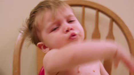 An-adorable-little-boy-in-a-high-chair-booster-seat-eating-messy-food-with-his-hands