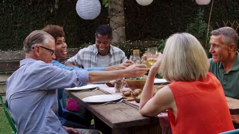 Amigos-maduros-disfrutando-de-comida-al-aire-libre-en-el-patio-trasero-rodado-en-R3D