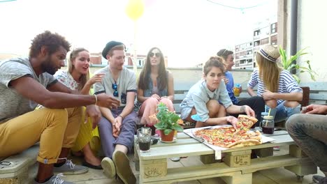 Attractive-young-people-sitting-around-the-table-on-the-rooftop-terrace