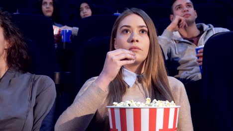 Girl-slowly-puts-the-popcorn-in-her-mouth-at-the-movie-theater