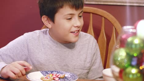 Young-boy-eating-from-a-bowl-of-gingerbread-cookie-decorations