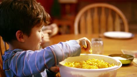 Joven-sacando-macarrones-y-queso-en-el-plato-en-la-mesa-de-la-cena