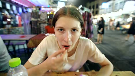 Primer-plano-de-mujer-turista-comer-bocadillo-de-larva-de-gusano-de-seda-en-comida-callejera-descansante-asiático