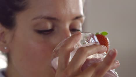 Mujer-bebiendo-batido-y-luego-comiendo-fresa,-de-cerca,-rodada-en-R3D