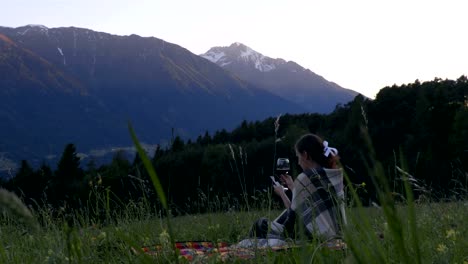 Junge-Dame,-die-den-Wein-und-Sonnenuntergang-in-Alpen-genießen