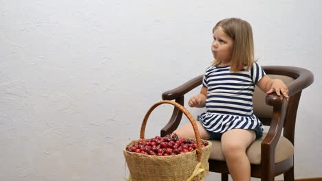 Cute-little-girl-eat-a-cherries-at-the-chair