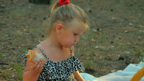 Entzückendes-kleine-Mädchen-essen-Croissant-im-park