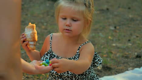 Niña-come-un-croissant-y-trata-de-un-colorido-dulces-de-la-mano-de-la-hembra