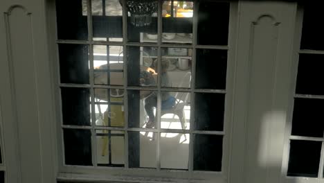 Family-having-breakfast,-view-through-house-window