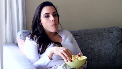 Beautiful-woman-eating-popcorn-on-sofa-4k