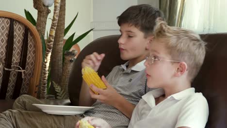 Dos-niños-están-comiendo-un-maíz