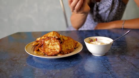 Young-Woman-Takes-Delicious-Fried-Vegetable-Pancake,-Dunked-In-Sauce-And-Eat