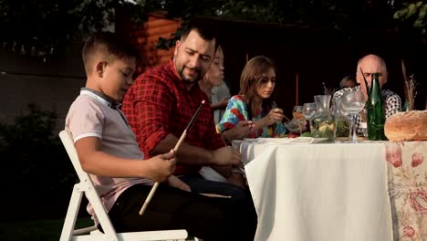 Niño-juguetón-con-palillos-del-tambor-en-la-mesa