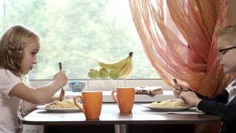 Los-niños-pequeños-lindos-tienen-una-cena-en-la-cocina