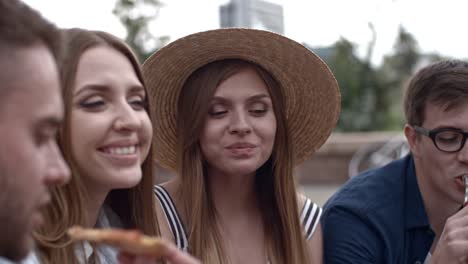 Young-Company-of-Friends-Eating-Pizza-while-Meeting-Outdoors