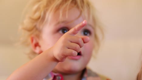 Kleinkind-Kleinkind-Baby-Boy-mit-am-Bildschirm-Aufmerksamkeit-und-mit-einer-fixierten-hypnotisiert-Blick-auf-seine-ausdrucksstarke-Gesicht.-Blonde-Jungen-hinweisen-auf-Leinwand-mit-einem-überrascht-expressiven-Ausdruck-auf-seinem-Gesicht-in-4-k-Auflösung