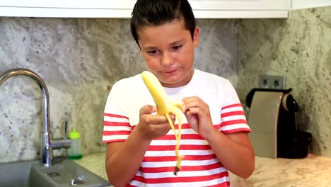 Young-boy-eating-banana-in-the-kitchen