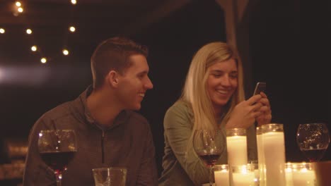 Young-loving-couple-looking-at-her-cell-phone-while-at-a-dinner-table