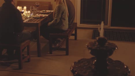 Panning-shot-of-young-people-having-dinner-at-a-patio-table