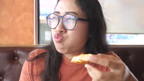 Young-woman-eats-pizza-in-restaurant