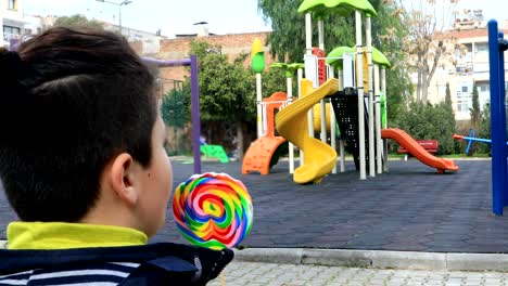 niño-comiendo-piruleta-en-el-patio-de-recreo