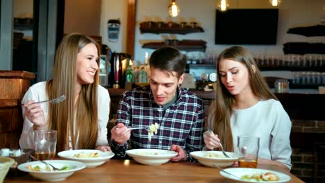 Happy-friends-sitting-in-cafe-while-eating.