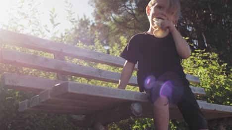 Little-kid-eating-bread-on-a-bench-at-the-park.-Lense-flare