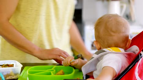 Mother-preparing-breakfast-for-her-baby-boy-in-kitchen-4k