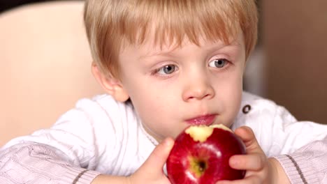 Niño-es-morder-manzana-roja-sentado-en-la-mesa.