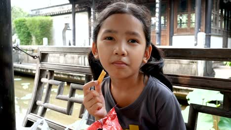 Cute-Asian-little-girl-eating-snack-with-happiness