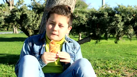 Young-boy-eating-croissant-at-the-outdoors