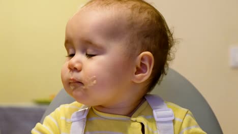 Mom-feeds-the-infant-with-baby-food-from-a-jar,-the-baby-girl-is-napping-and-does-not-want-to-eat-close-up