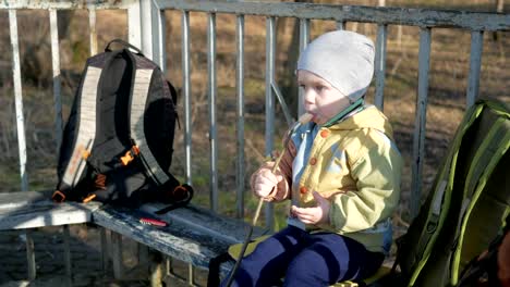 Ein-hübscher-Junge-isst-eine-Wurst-außerhalb.-Am-Feuer-grillen-gekocht