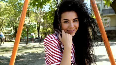 Charming-brunette-swinging-and-eating-ice-cream-on-the-playground