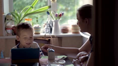 Mamá-jugando-con-el-hijo-y-el-bebé-que-está-lactando-durante-el-desayuno