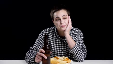 Young-mannish-girl-is-drinking-beer,-thhinking,-potato-chips-on-plate,-diet-conception,-black-background-50fps