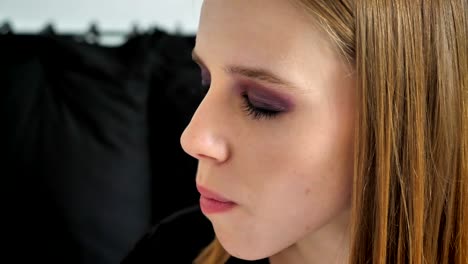 Young-beautiful-women-with-heavy-make-up-eating-cake-with-closed-eyes,-black-sofa-background